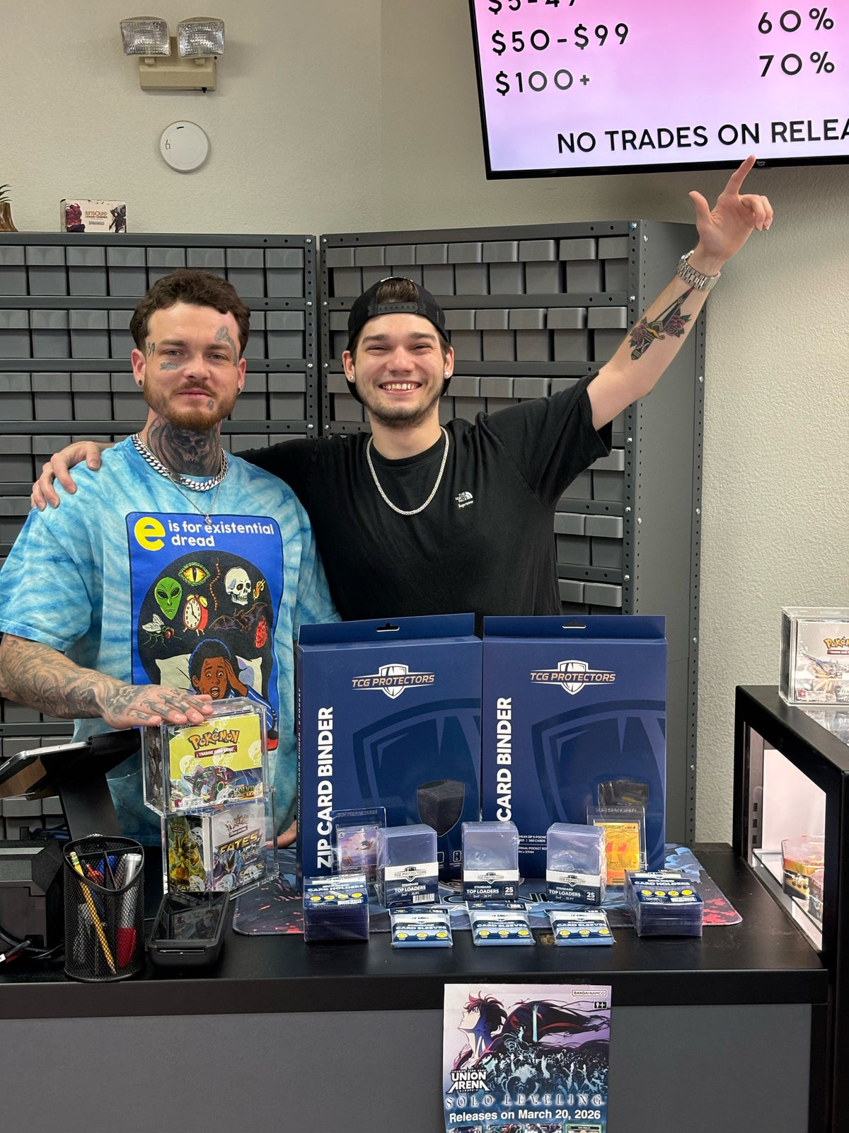 Two Phoenix Cards employees holding TCG Protectors cases