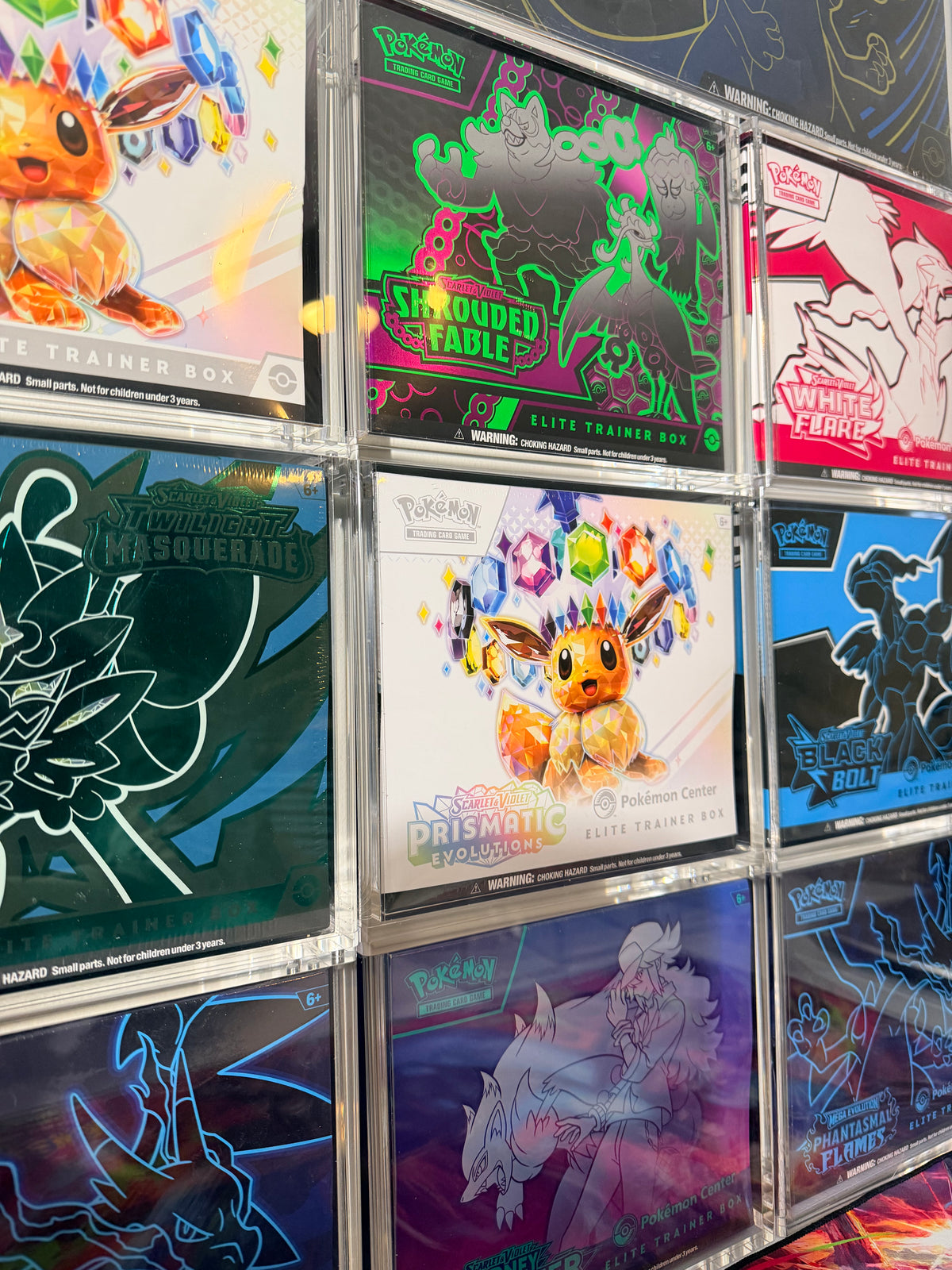 Wall of sealed Pokémon Elite Trainer Boxes in TCG Protectors acrylic display cases