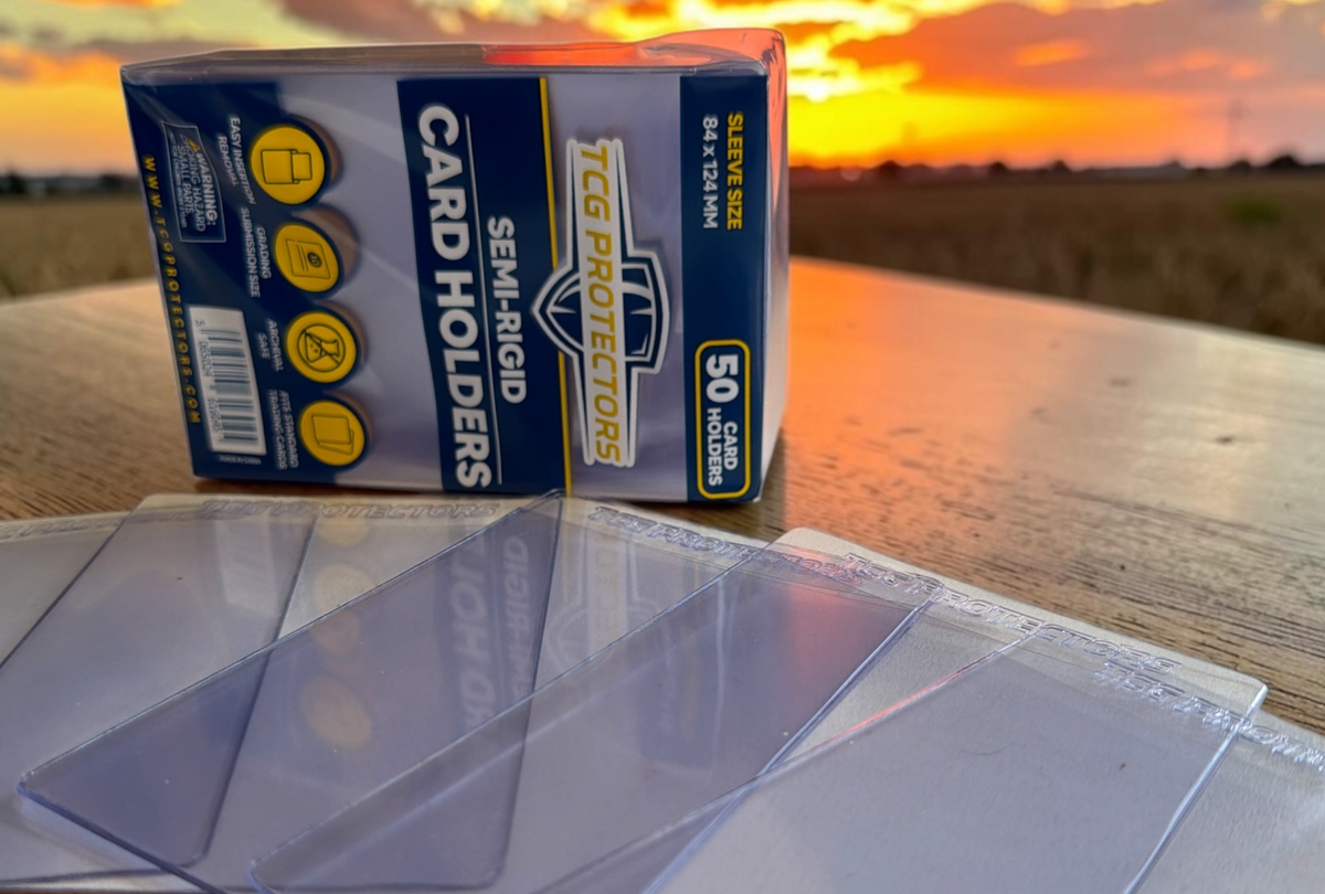 Box of TCG Card Holders with clear card protectors on a wooden surface at sunset.